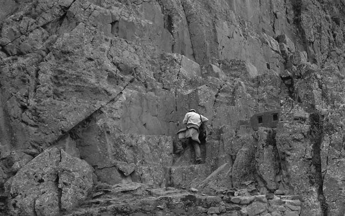 Рис. 28. Участник экспедиции Александр Дымников (на скале) осматривает площадку с пропилами.